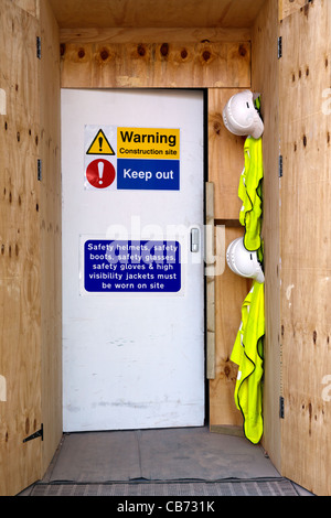 Photo of the entrance to a construction site with health and safety notices, hard hats and high visibility jackets. Stock Photo