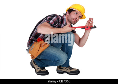 Man using a pipe wrench to tighten a pipe Stock Photo