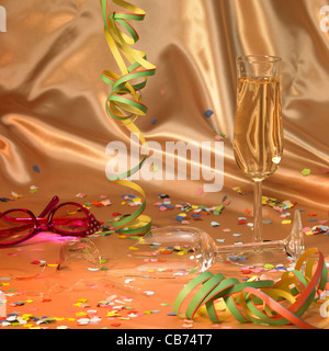 carnival background with a filled and a broken champagne glass in floating satin back with streamers and confetti Stock Photo