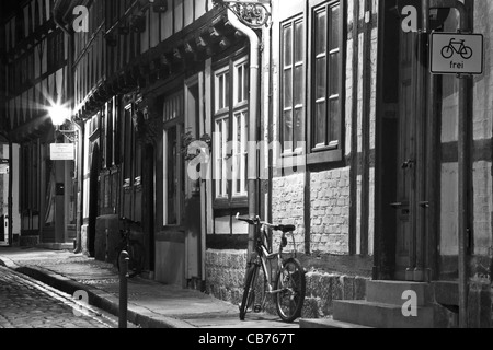 A narrow cobbled street of timber framed houses and a bicycle at night in Quedlinburg, Germany.  Color version available: CB77HC Stock Photo