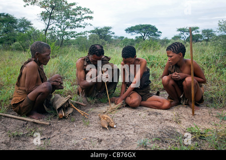 Bushman / San making fire by hand with wooden stick in the Kalahari desert near Ghanzi, Botswana, Africa Stock Photo