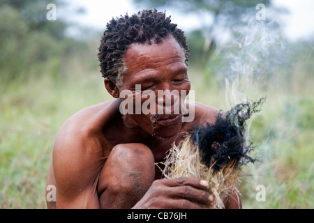 Bushman starting fire in the Kalahari desert near Ghanzi, Botswana, Africa Stock Photo