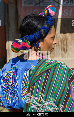 An indigenous Central American Indian woman in traditional woven clothing and with colored braids and pom-poms in her hair. Stock Photo