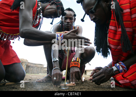 Young Masai men start a friction fire by rubbing two sticks together at their village in the Masai Mara National Reserve, Kenya. 2/2/2009. Photograph: Stock Photo