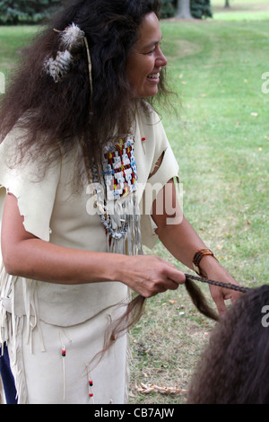 A Native American Indian woman braiding the hair of young boy Stock Photo