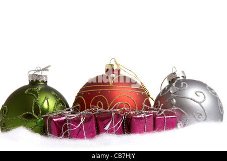 Three christmas baubles and some small gifts in colored wrapping paper isolated on white background Stock Photo