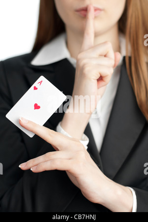Young businesswoman holding ace of hearts in her hand before her and her finger at her lips (silence gesture). Isolated on white Stock Photo