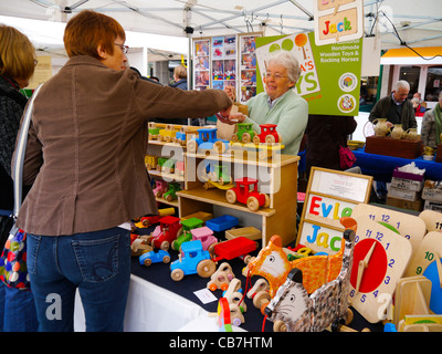 Female customer buying wooden toys at Made in Shropshire market stall Shrewsbury Shropshire Stock Photo