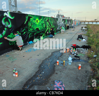 Group of young people spray painting a legal graffiti wall. Stock Photo
