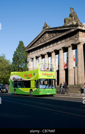 An open top double deck tour bus passes the Royal Scottish Academy Building in Princes Street, Edinburgh. Stock Photo