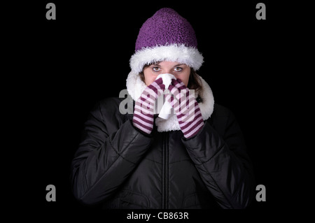 young woman in winter clothes having a cold. isolated on black background Stock Photo