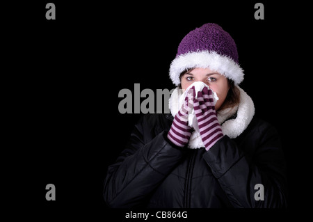 young woman having blowing her nose. Isolated on black Stock Photo