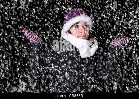 snowstorm: snowing on young woman in winterclothes looking up Stock Photo