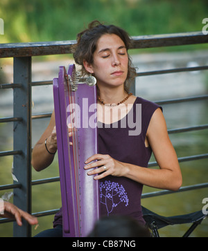 Concentrated young musician playing celtic harp. Berlin, Kreuzberg, Germany. Stock Photo