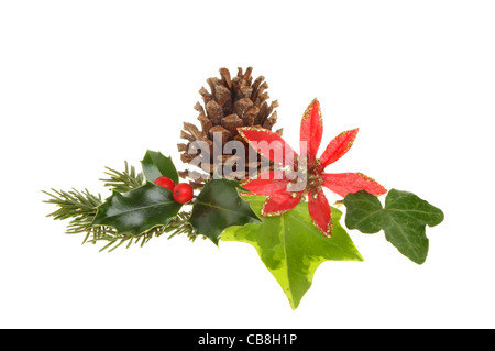 Christmas seasonal foliage, holly,ivy,pine needles, pinecone and an artificial red and gold flower isolated on white Stock Photo