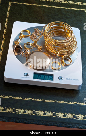 Weighing variety of old gold jewellery on portable digital desk weighing machine displaying weight in ounces Stock Photo
