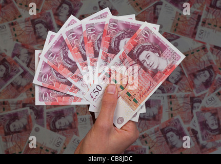 Hand full of new £50 fifty pound notes against background of 50 bank notes Stock Photo