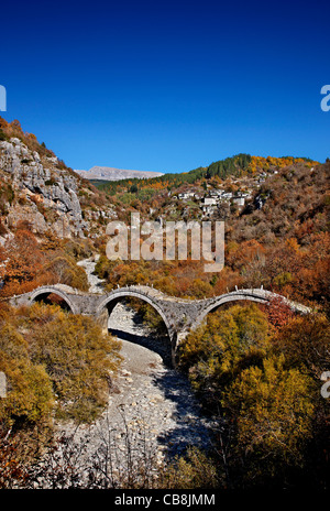 The 3- arched stone bridge known as 'Kalogeriko' or 'Plakidas' bridge, Zagori region, Ioannina, Greece. In the BG, Kipoi village Stock Photo