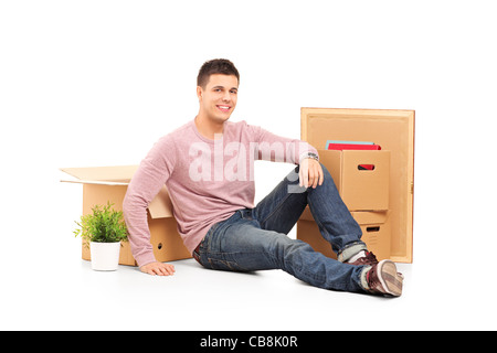 Smiling man resting from moving into a new home with boxes around him Stock Photo