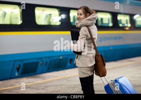 Train is coming - young woman waiting for her connection in a modern train station (shallow DOF) Stock Photo