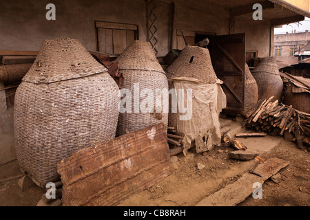 India, Nagaland, Jakhama Village, closely woven rat-proof rice storage baskets outside house Stock Photo