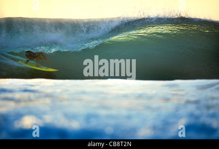 Surfing deep in the tube on a sunset emerald wave. Desert Point, Lombok, Indonesia, Southeast Asia, Asia Stock Photo