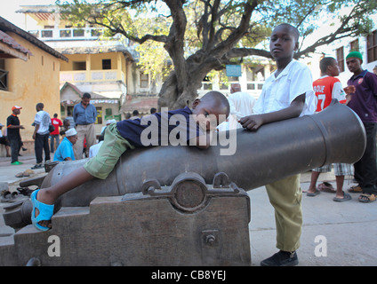 Little Boy Lazing On A Cannon In  A Street Of Lamu, Kenya Stock Photo