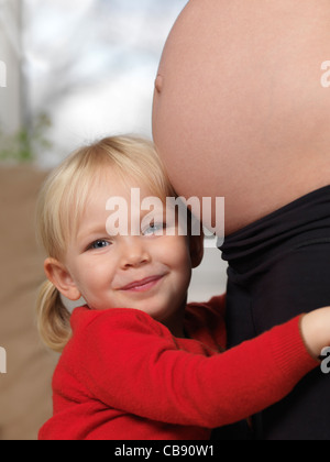 Pregnant mother and her happy smiling three year old little daughter together Stock Photo