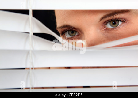 Woman peering through some blinds Stock Photo