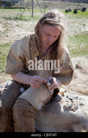 Neolithic re-enactment. Stone Age man holding fish spear in animal hide ...
