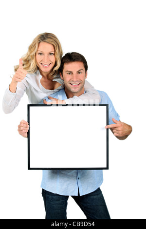 Excited couple pointing to a blank sign Stock Photo