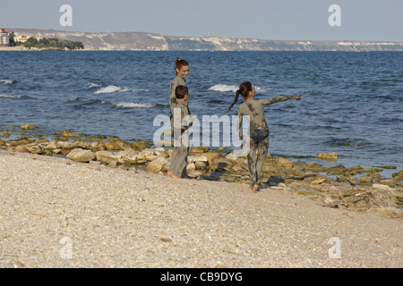 Kids covered with a healing mud play on the beach, Tuzlata resort near town of Balchik, Black Sea Coast, Bulgaria Stock Photo