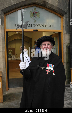 Senior man carrying pike staff and wearing medals at the entrance to Durham town hall, north east England, UK Stock Photo