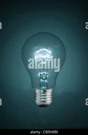 A traditional tungsten, screw-fit  light bulb. Illuminated - though not visibly connected to an electrical supply. Stock Photo