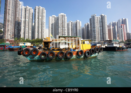 working boats and house boats in aberdeen harbour in front of apartment buildings in hong kong hksar china Stock Photo