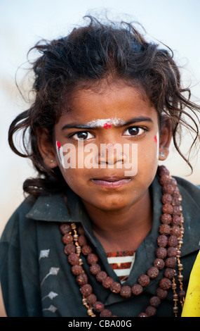 Poor Indian beggar girl dressed in religious hindu attire. Selective focus. Stock Photo