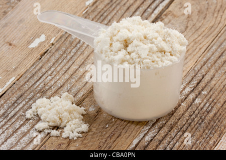 scoop of whey protein isolate powder on a grunge wooden table background Stock Photo