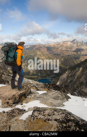 Backpacker at Aasgard Pass overlooking Colchuck Lake and the Eightmile Creek Valley in the Alpine Lakes Wilderness Area. Stock Photo