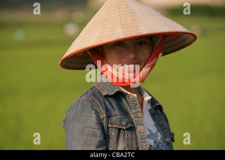 Vietnamese woman working in rice paddy with Vietnamese conical sedge hat Stock Photo
