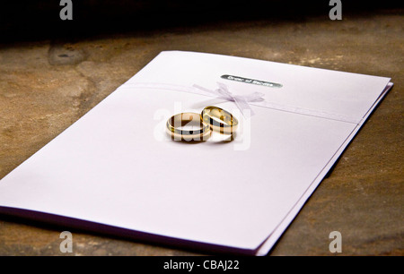 two yellow gold wedding rings on a order of service.landscape format Stock Photo