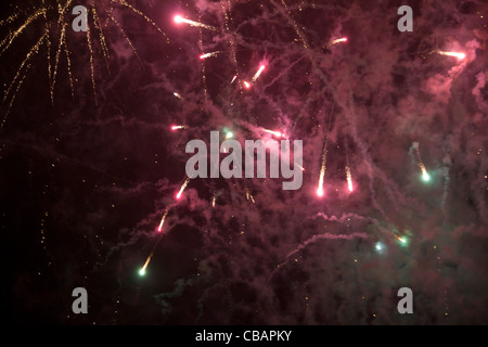 Fireworks display in London. Red lights shoot off in different directions creating a cloud of dust filling up the night sky. Stock Photo