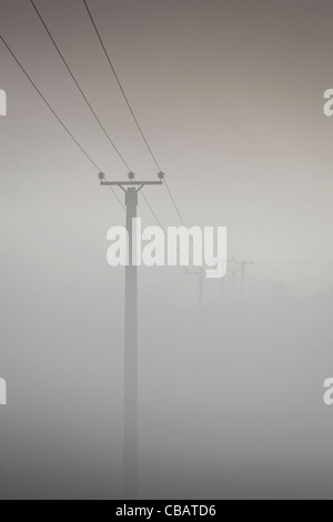 Power lines stretch across the hillside on a foggy cold morning in Yorkshire UK Stock Photo