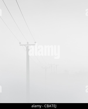 Power lines stretch across the hillside on a foggy cold morning in Yorkshire UK Stock Photo