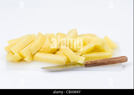 raw potatoes cut up to make chips on a white chopping board against a white background Stock Photo