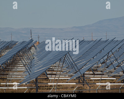 A series of large solar panels forms a symmetrical line at a power plant in the San Luis Valley of central Colorado. These panels utilize a tracking system to follow the sun, collecting its energy and using photovoltaic cells to transform the sunlight into electricity. Stock Photo