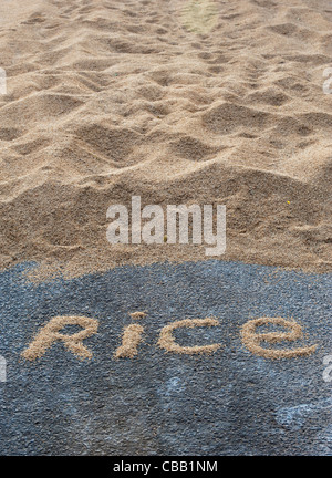 RICE word in front of Drying rice grain on an Indian road. Andhra Pradesh, India Stock Photo