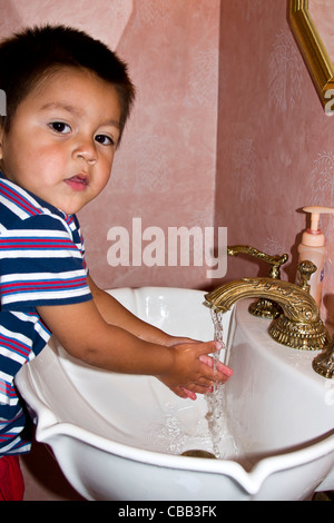 Hispanic boy washing his hands in sink with soap and running water eye contact looking at camera MR © Myrleen Pearson Stock Photo