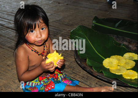 Embera indian little girl eating pineapple at Embera Puru indigenous community, Panama Stock Photo