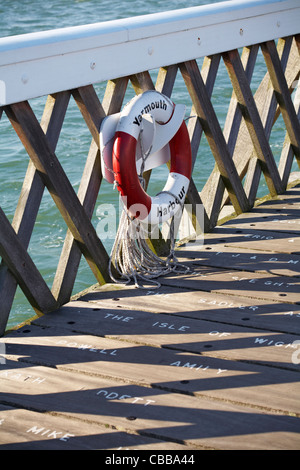 Yarmouth Harbour lifebuoy lifering life ring on pier showing dedication names on planking of pier in September at Yarmouth, Isle of Wight Hampshire UK Stock Photo