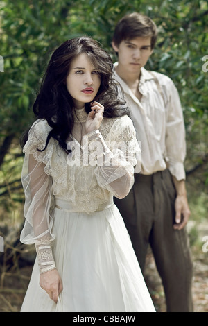 A young woman with long black hair walking away from a young man dressed in period costume Stock Photo